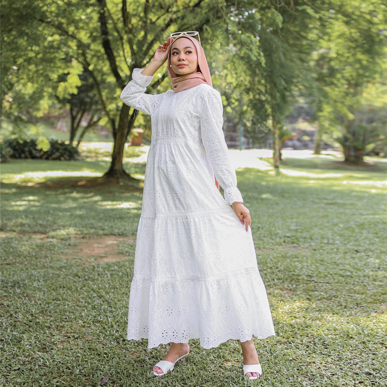 Woman in a white dress standing in a park with greenery