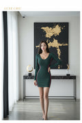 Woman wearing a green dress with pink accents in an indoor setting