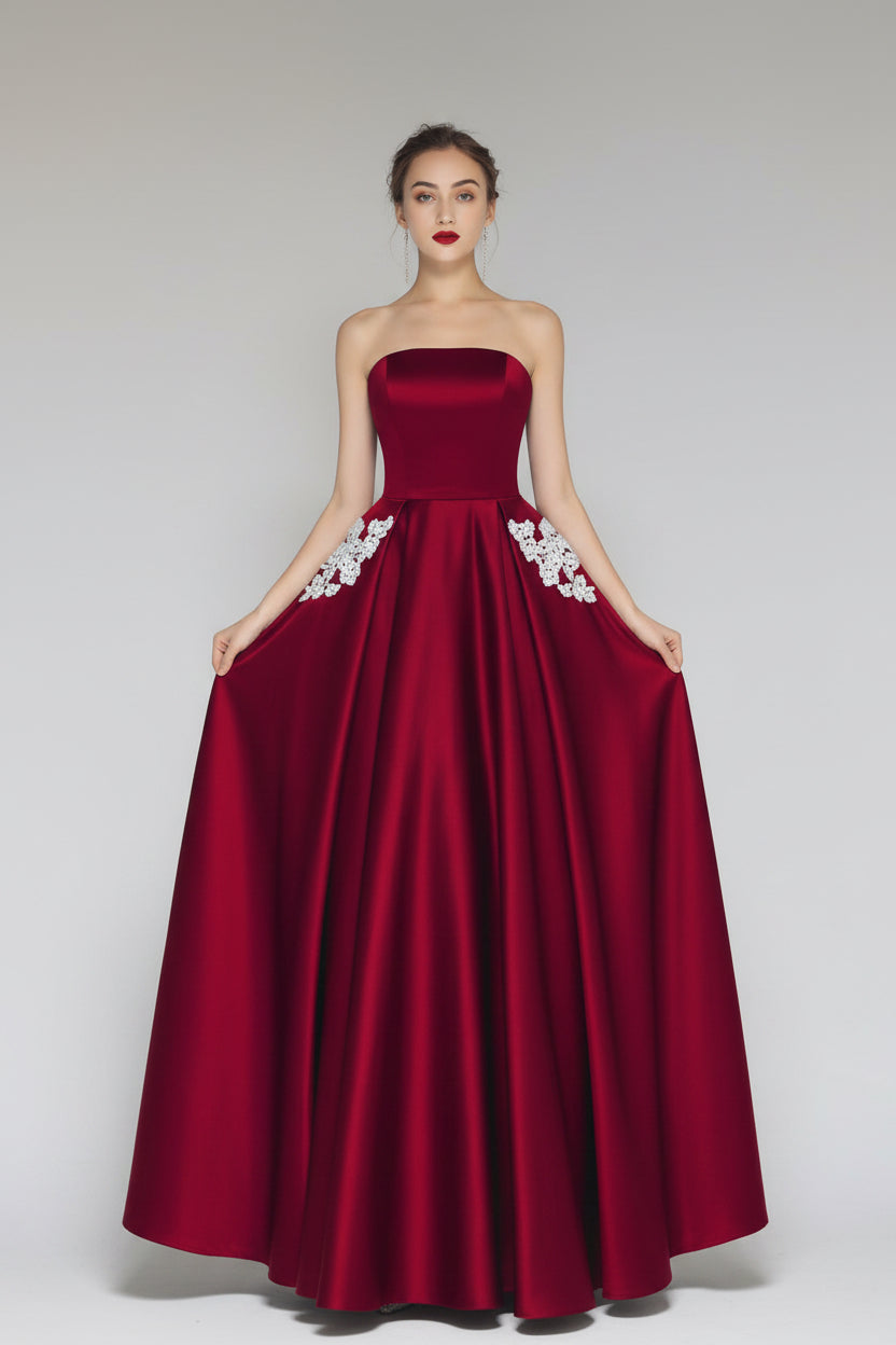 Red strapless gown with white floral details on a plain background