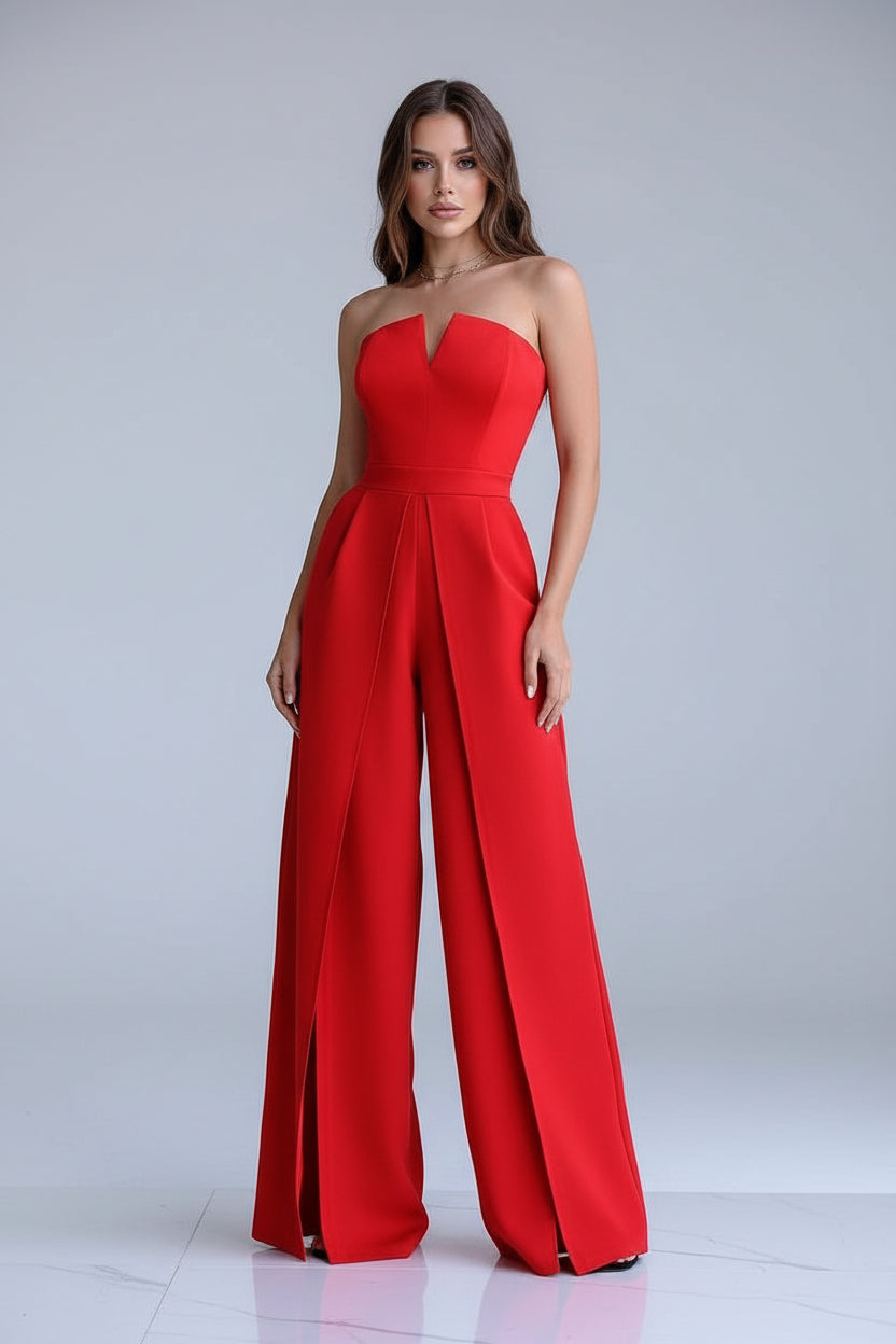 Red strapless jumpsuit worn by a model in a stylish room with decorative elements.