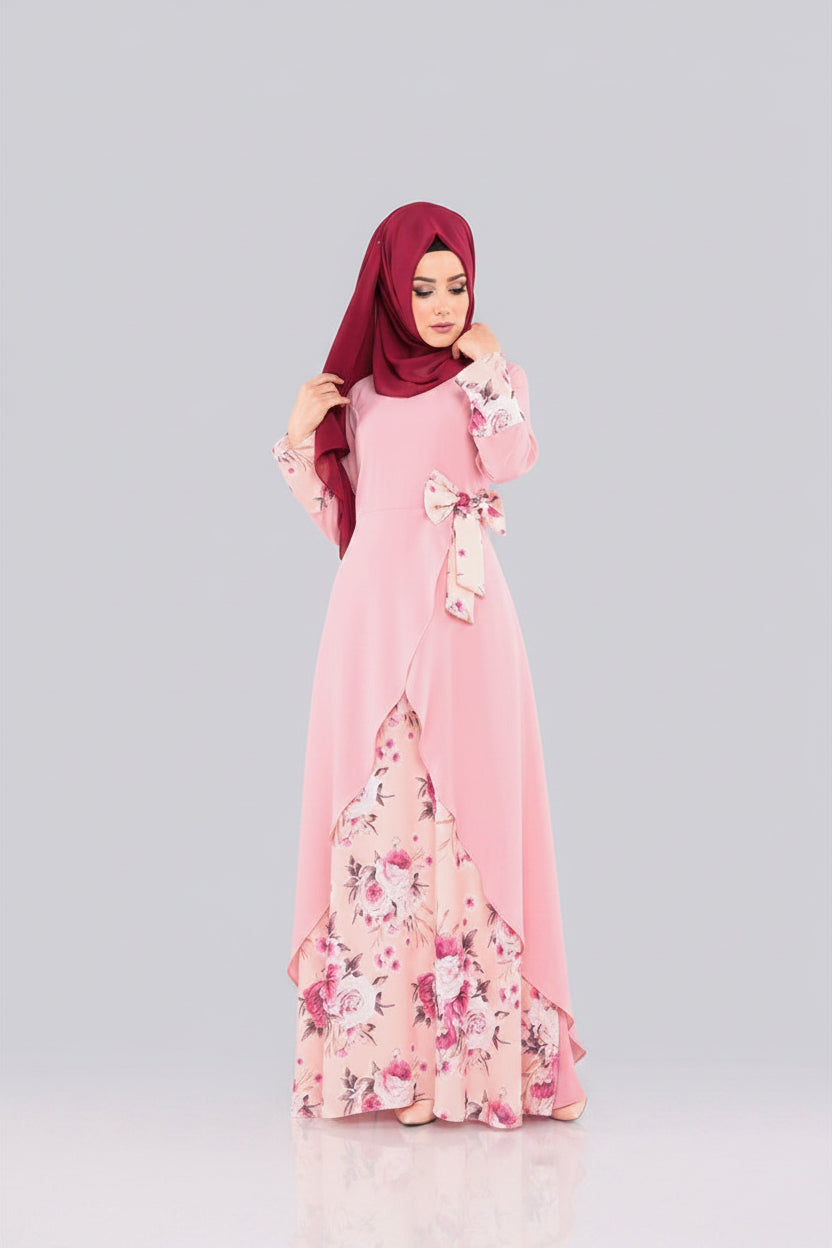 Woman wearing a pink floral dress with a matching hijab on a gray background
