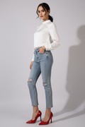Red high-heeled shoes worn with light blue jeans on a neutral background