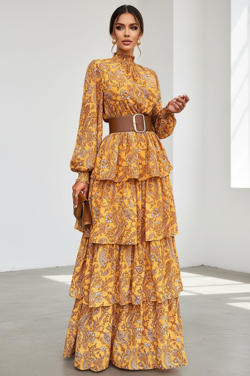 Woman wearing a layered, patterned dress with a belt in an outdoor setting.
