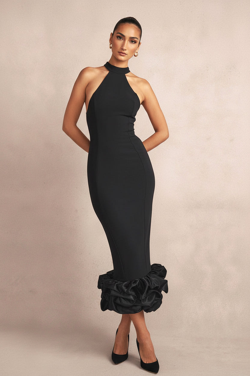Woman wearing a black dress with ruffled bottom section on a beige background