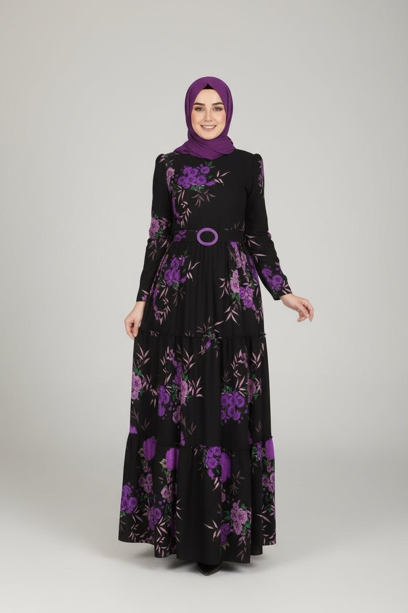 Woman in a black dress with purple floral patterns standing in an elegant indoor setting.