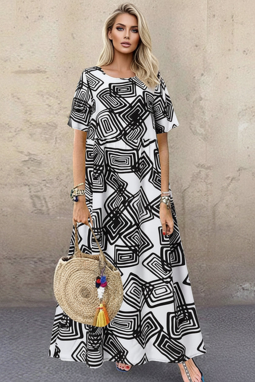 Woman wearing a black and white patterned dress holding a round straw bag against a wooden background