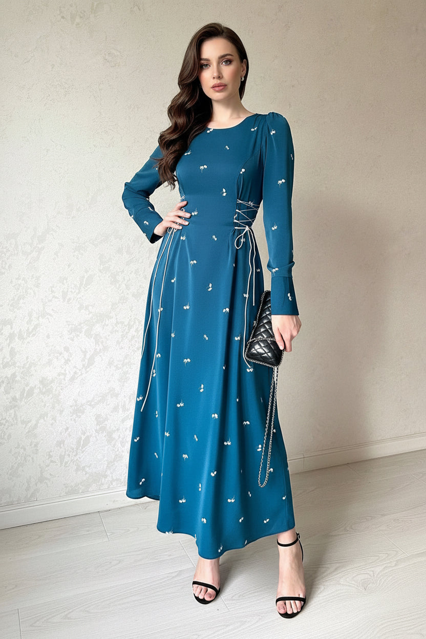 Woman wearing a blue dress with white patterns against a neutral background