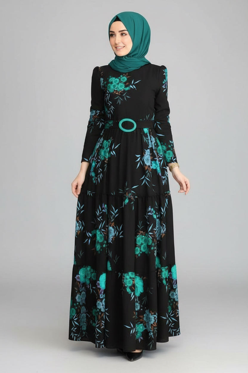Woman wearing a black dress with green floral patterns in an indoor setting.