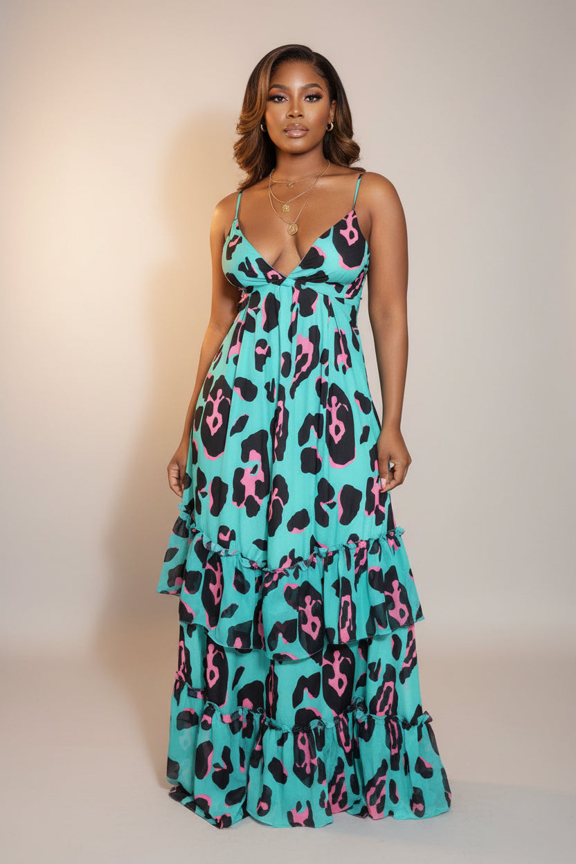 Woman wearing a turquoise dress with pink and black leopard print in an indoor setting.