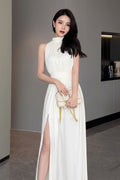 Woman in a white dress holding a matching handbag in an indoor setting.
