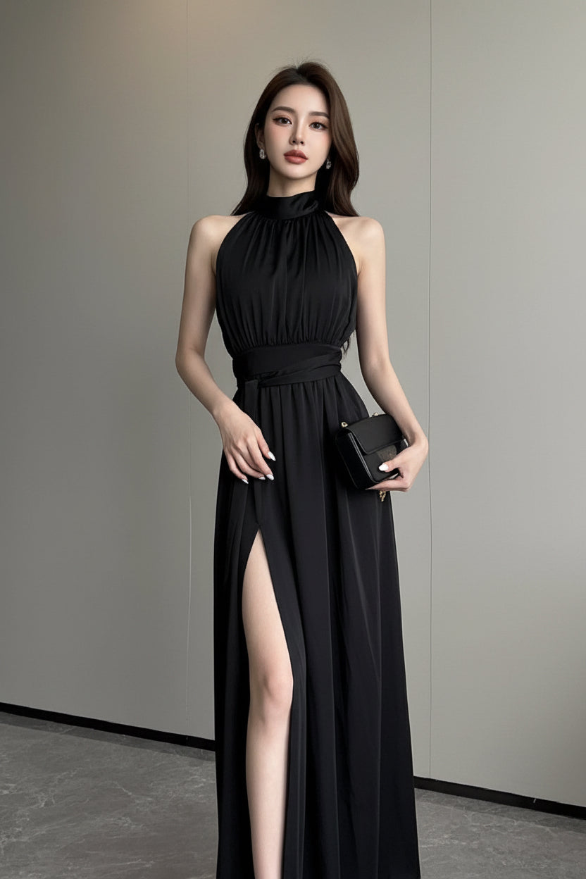 Woman wearing a black sleeveless dress with a high slit on a plain background