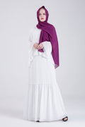 Woman wearing a white dress and purple hijab on a white background