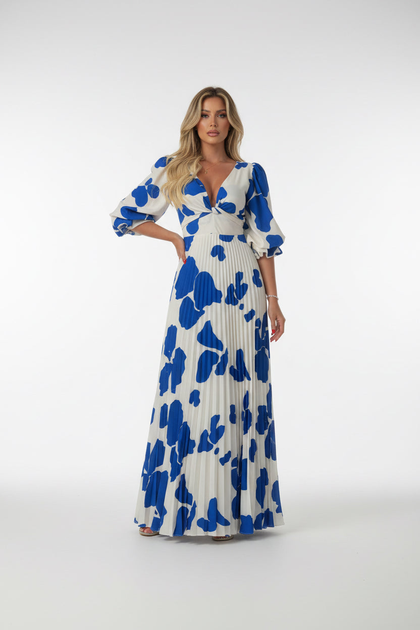 Woman wearing a blue and white floral dress standing in front of a store window with mannequins.