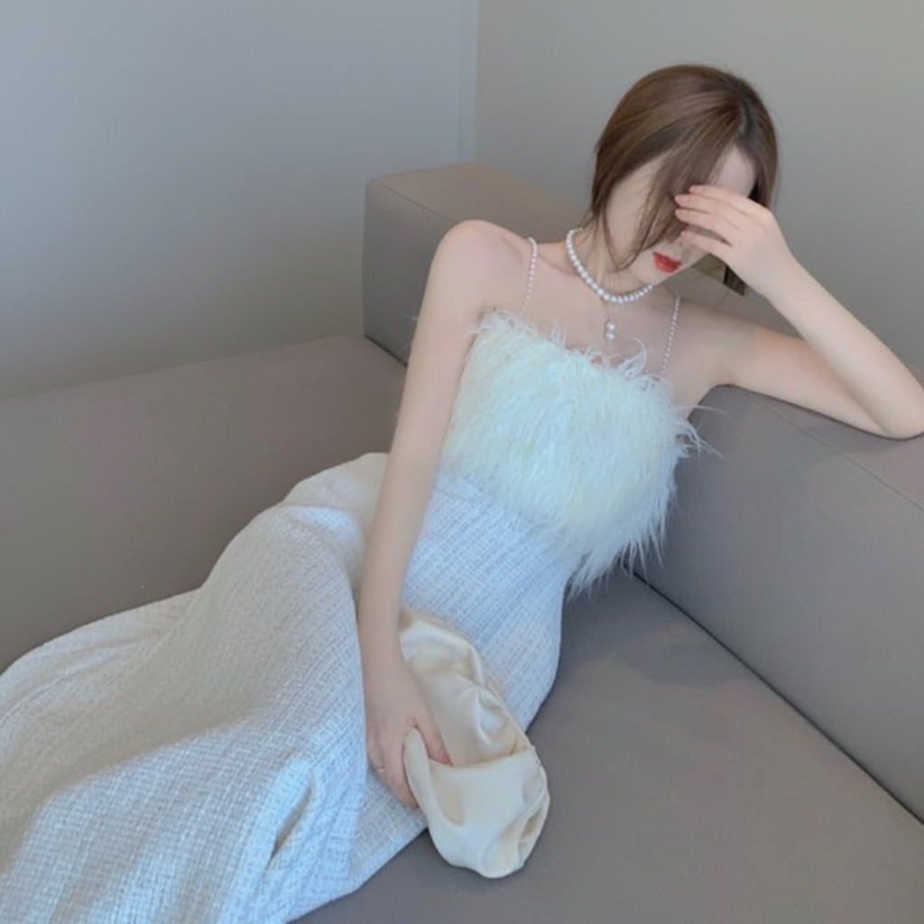 Woman in a light blue dress with feather details sitting on a gray couch.
