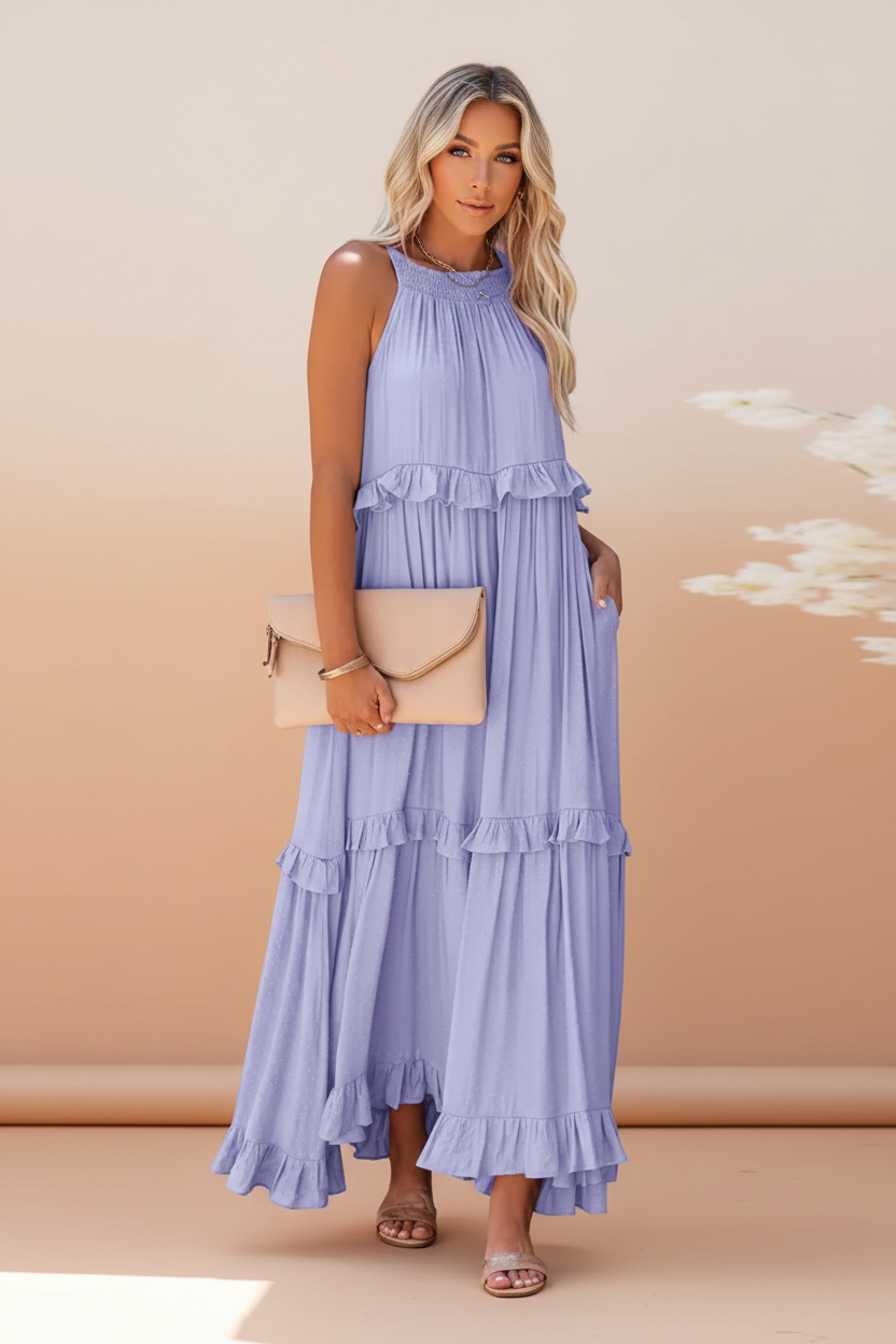 Woman wearing a long light blue dress with ruffled layers on a white background