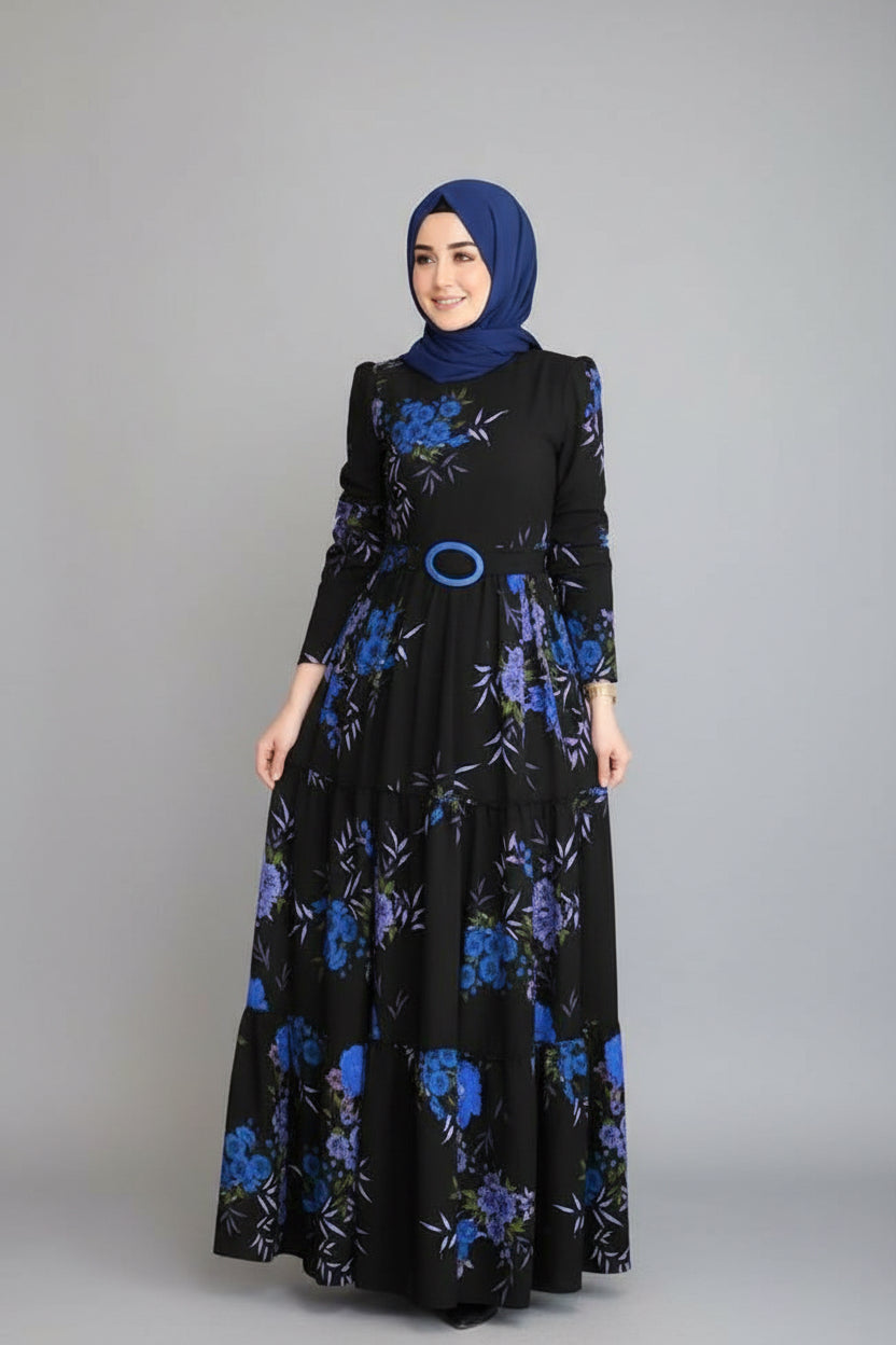 Woman in a black dress with blue floral patterns standing in an elegant indoor setting.