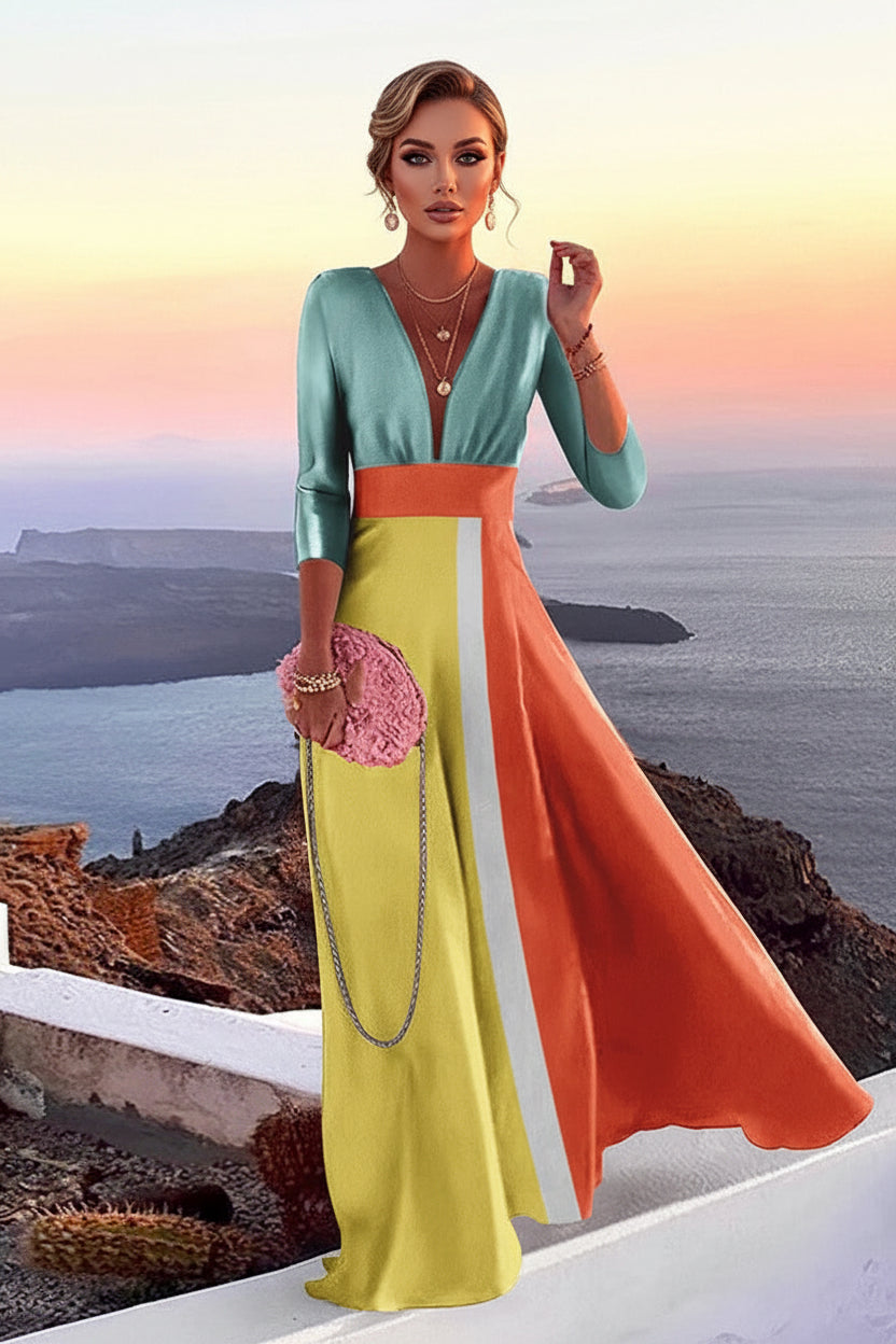 Woman in a colorful dress standing on a cliff with a scenic view of the ocean and sunset.