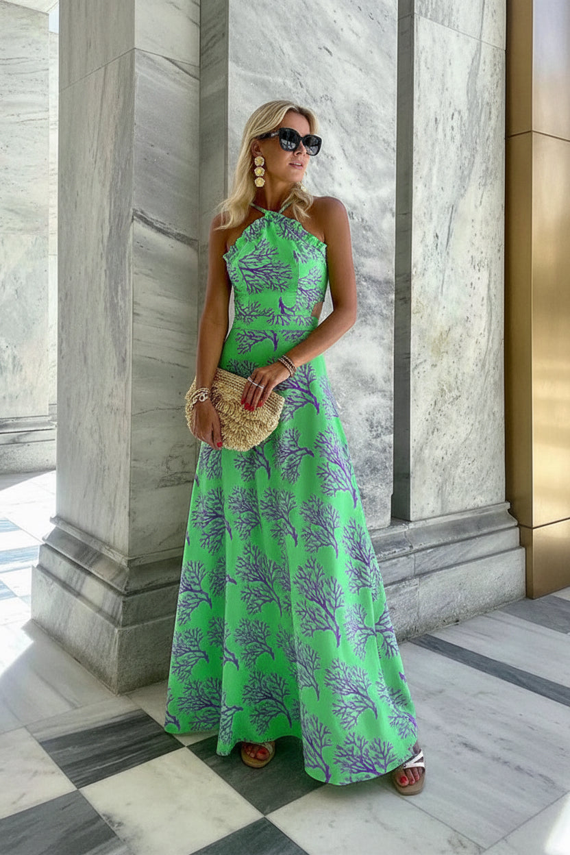 Woman in a green floral dress standing in front of a marble building.
