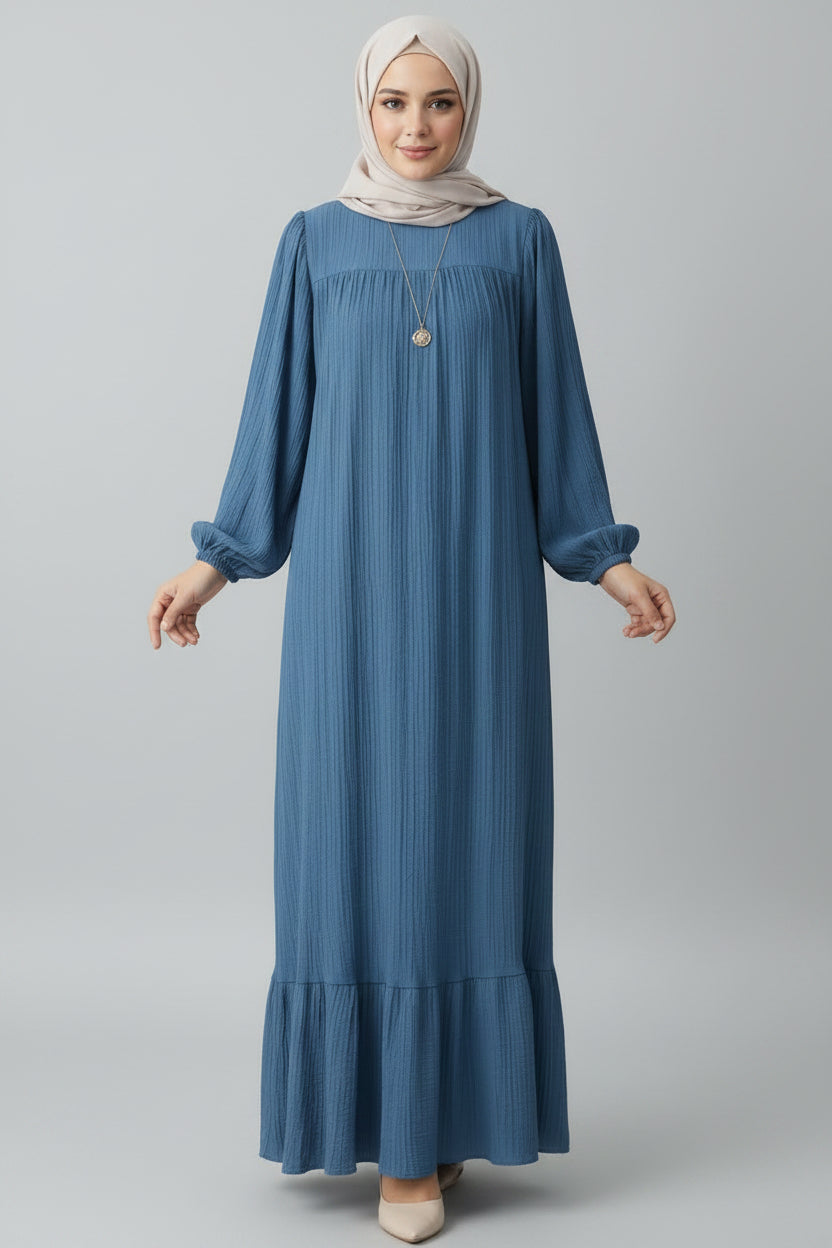 Woman wearing a blue dress in a minimalistic room.