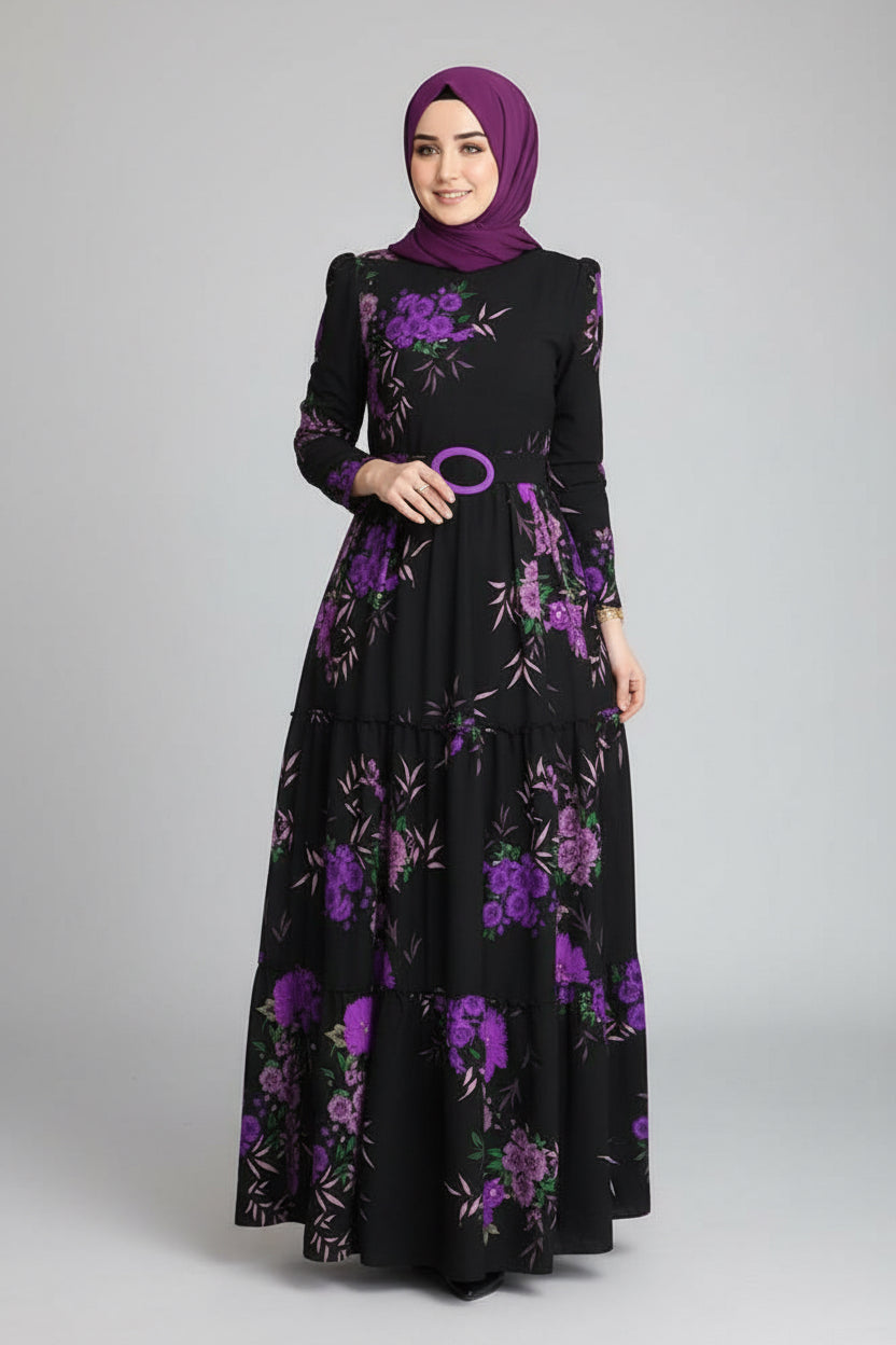 Woman in a black dress with purple floral patterns standing in an elegant indoor setting.