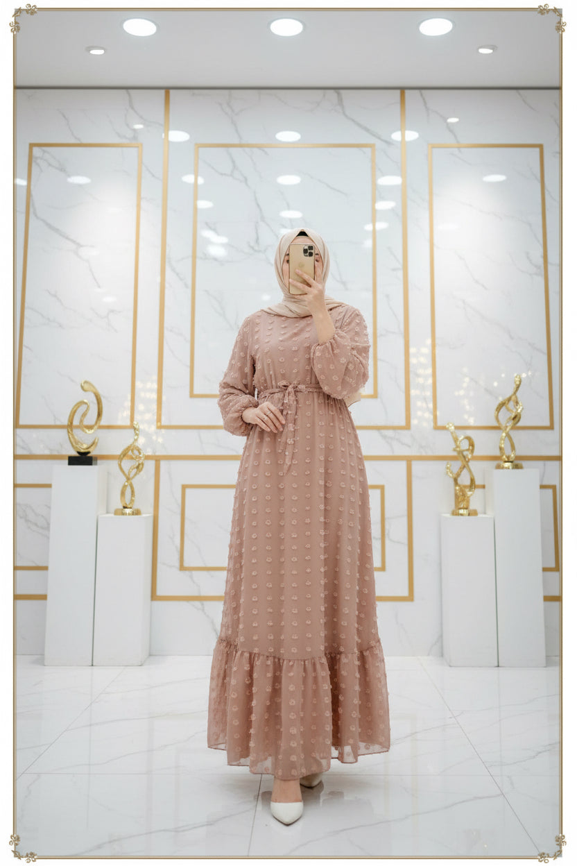 Person wearing a long, patterned dress standing in a bedroom.