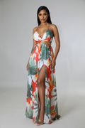 Woman wearing a colorful floral dress with a high slit on a plain background