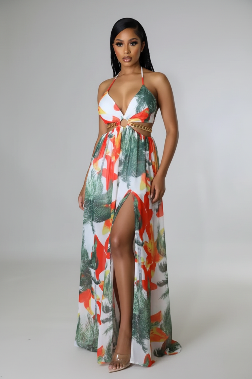 Woman wearing a colorful floral dress with a high slit on a plain background