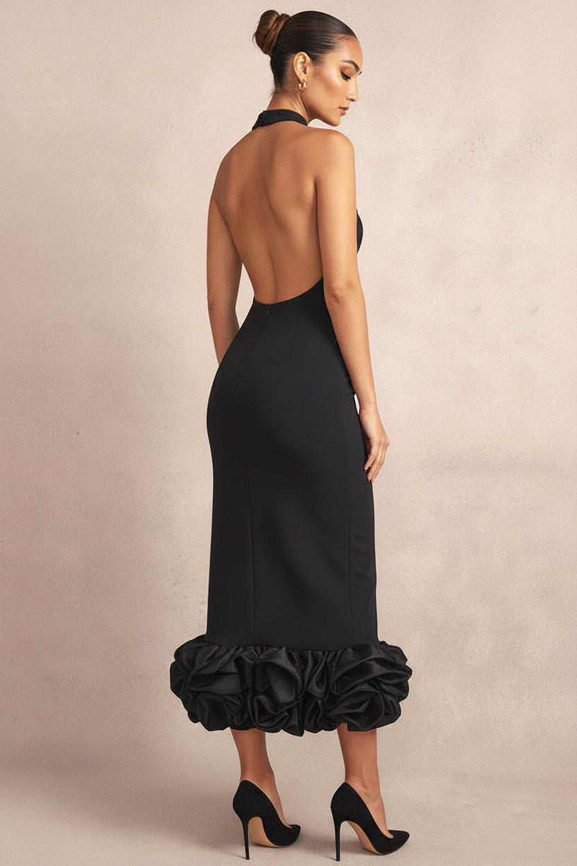 Woman wearing a black dress with ruffled bottom section on a beige background