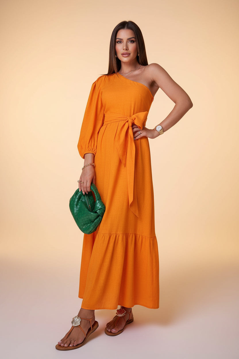 Woman in an orange dress holding a green bag with tropical plants in the background