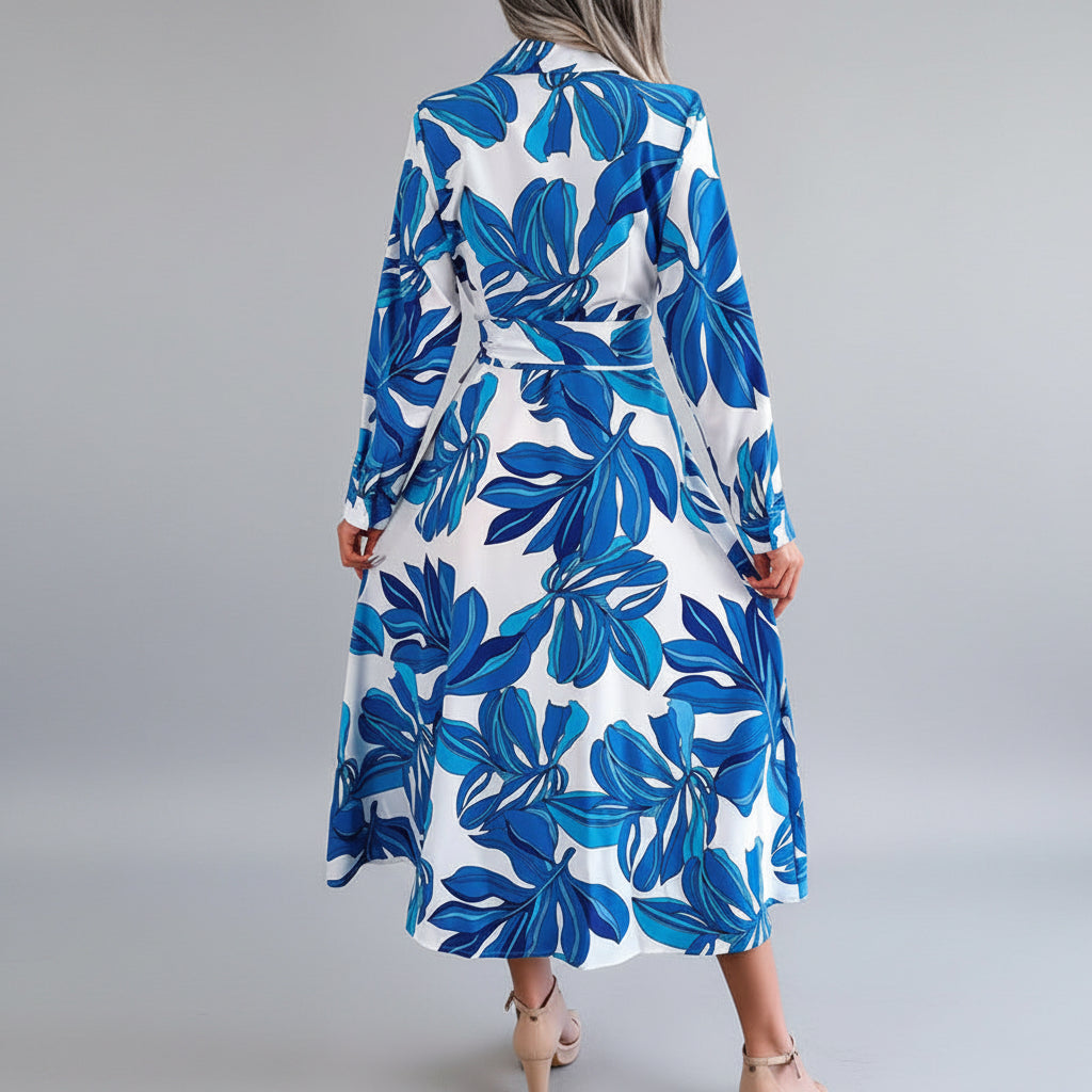Person wearing a blue and white floral dress in a room with a plant and sofa.