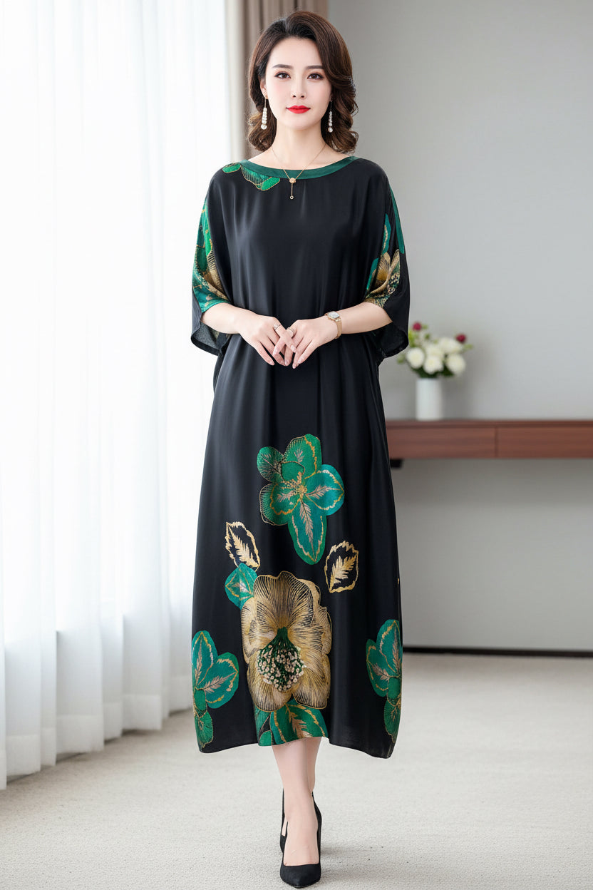Woman wearing a black dress with green floral patterns sitting on a gray couch.