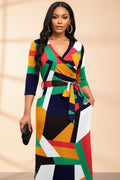 Colorful geometric patterned dress worn by a model on a white background
