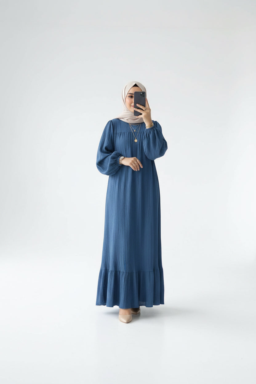 Woman wearing a blue dress in a minimalistic room.