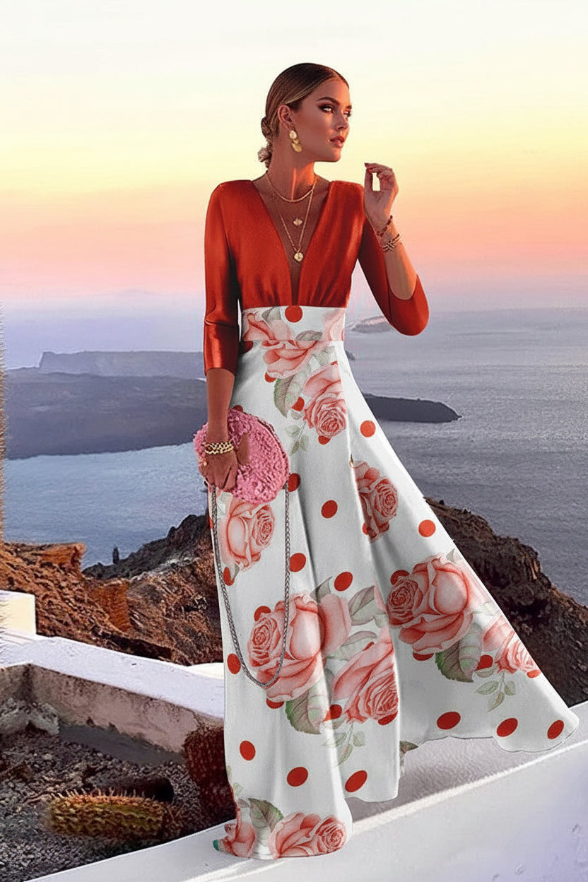 Woman in a floral dress standing on a cliff overlooking the ocean with a cactus plant nearby.