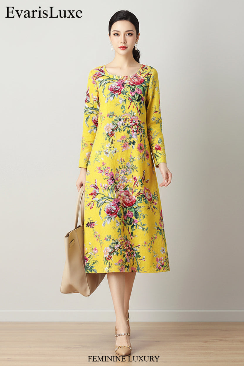 Woman wearing a yellow floral dress holding a beige handbag against a plain background