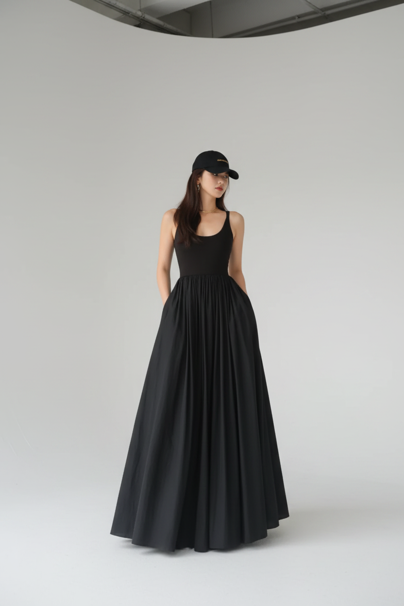 Woman wearing a black sleeveless dress and cap in front of a glass block wall.