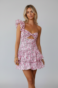 Woman wearing a pink floral dress with cut-out details against a white background