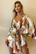 Woman wearing a tropical leaf patterned dress against a neutral background
