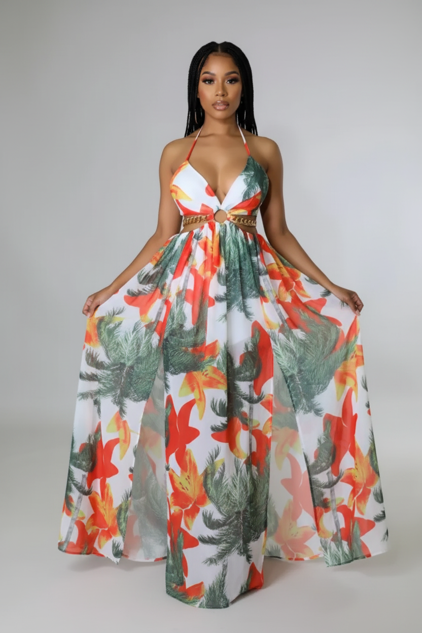 Woman wearing a colorful floral dress with a high slit on a plain background