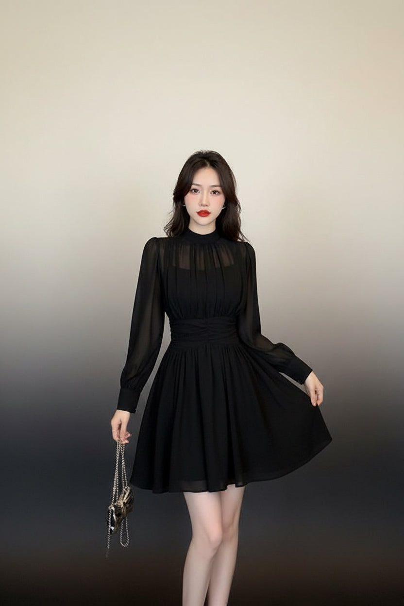 Woman wearing a black dress standing in a room with a door and wall.