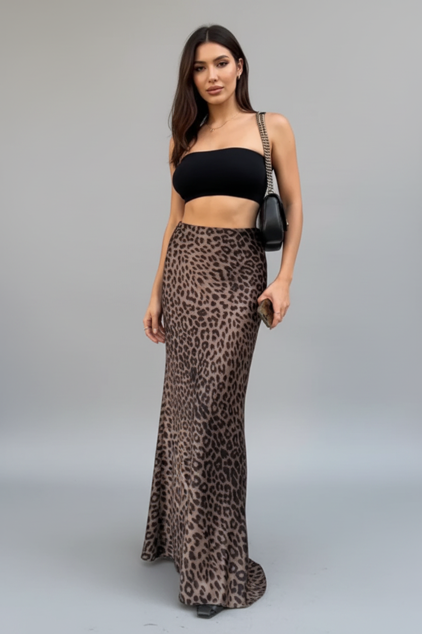 Woman wearing a black top and leopard print skirt standing against a building wall.