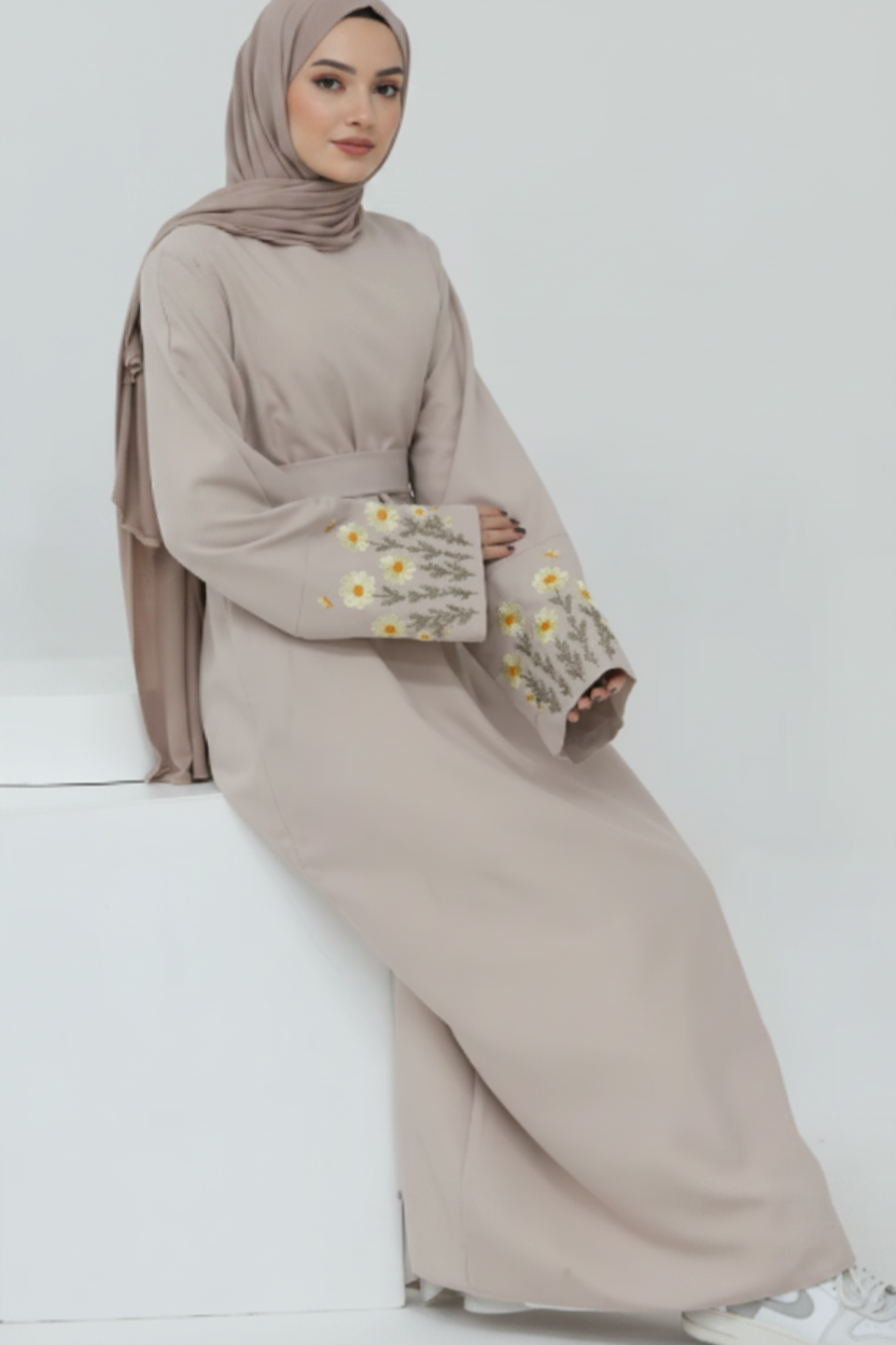 Beige outfit with floral embroidery on sleeves against a white background