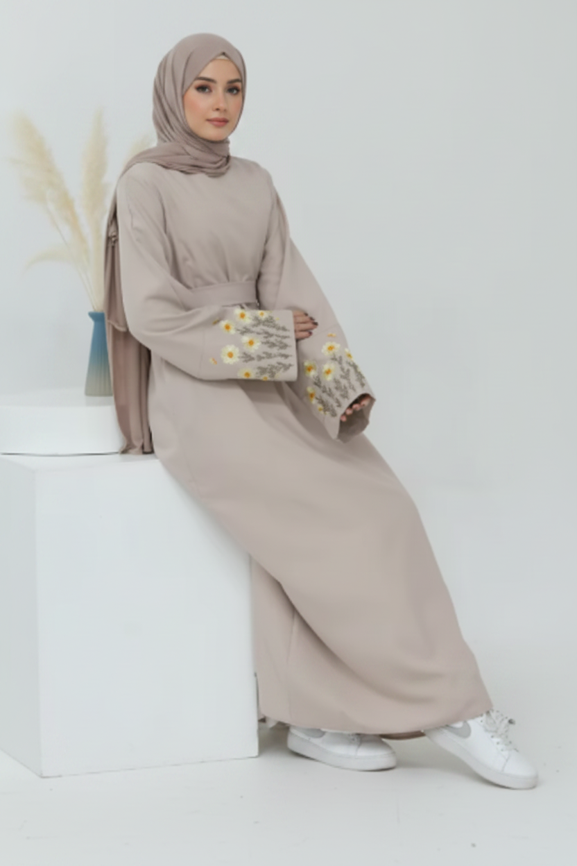 Beige outfit with floral embroidery on sleeves against a white background