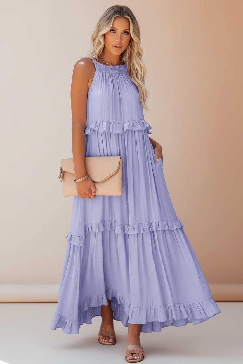 Woman wearing a long light blue dress with ruffled layers on a white background
