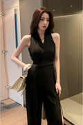 Woman in a black dress taking a mirror selfie in an indoor setting.