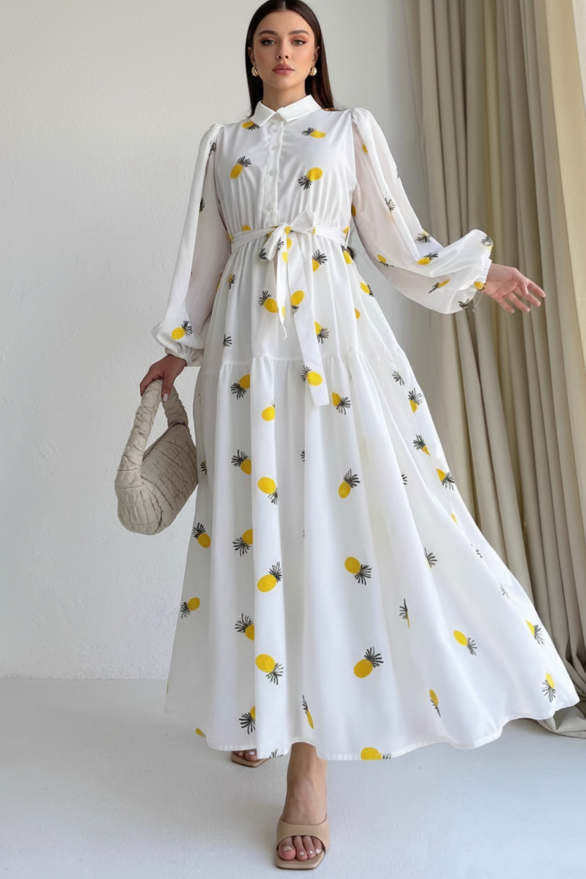 White dress with yellow pineapple pattern worn by a person indoors.