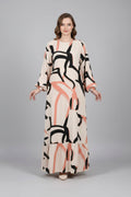 Person wearing a long dress with abstract pattern in a minimal indoor setting