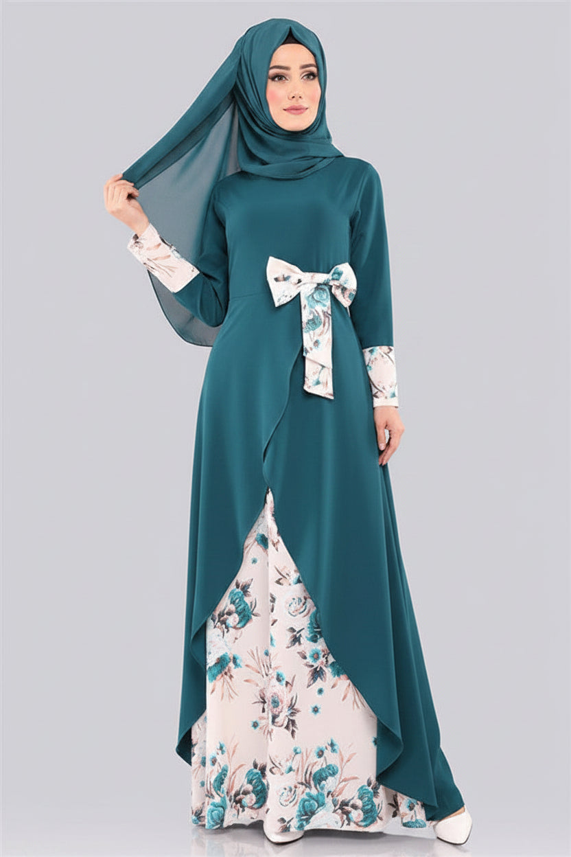 Woman wearing a teal abaya with floral patterns on a gray background