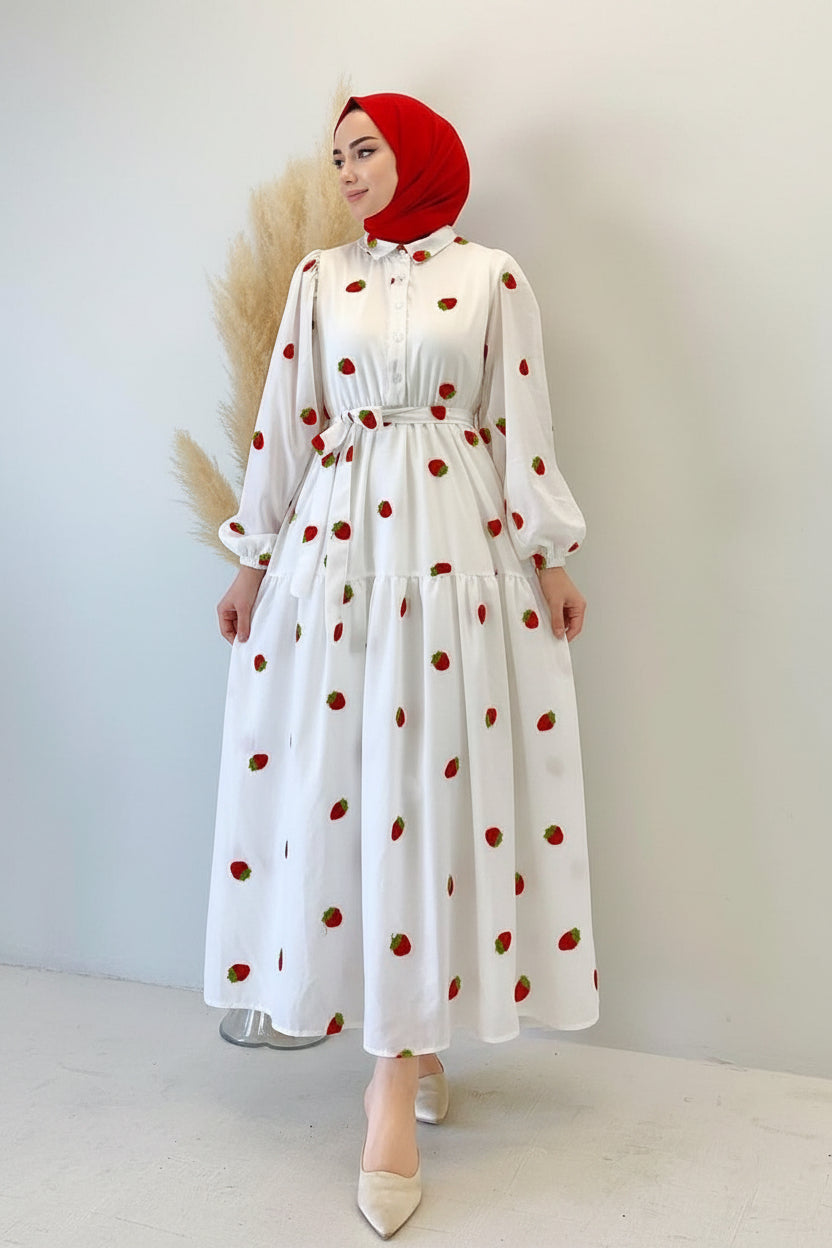 White dress with red polka dots worn by a person against a plain background