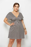 Woman wearing a black and white checkered dress against a plain background